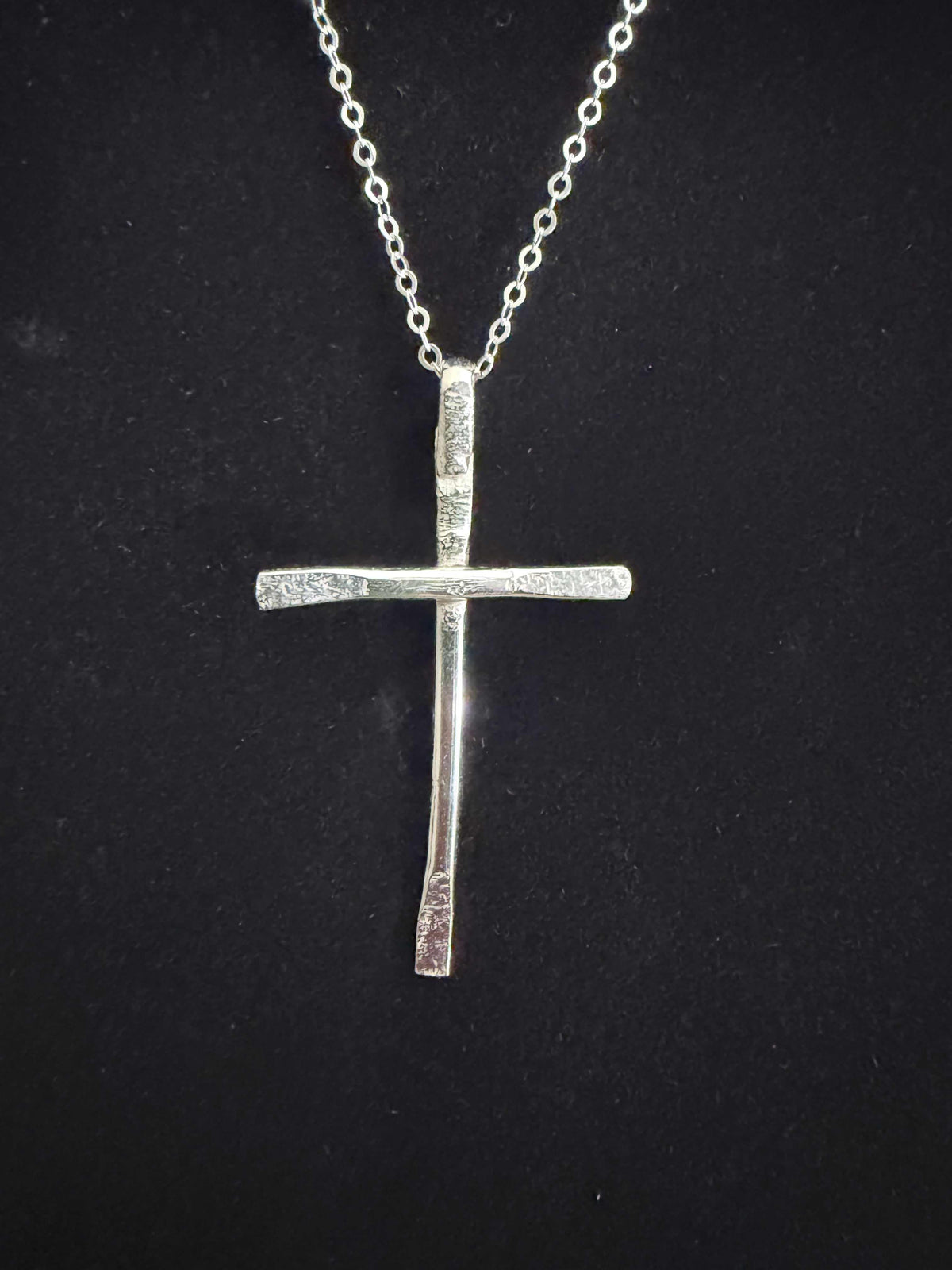 Close-up of the handcrafted sterling silver cross pendant and chain. 